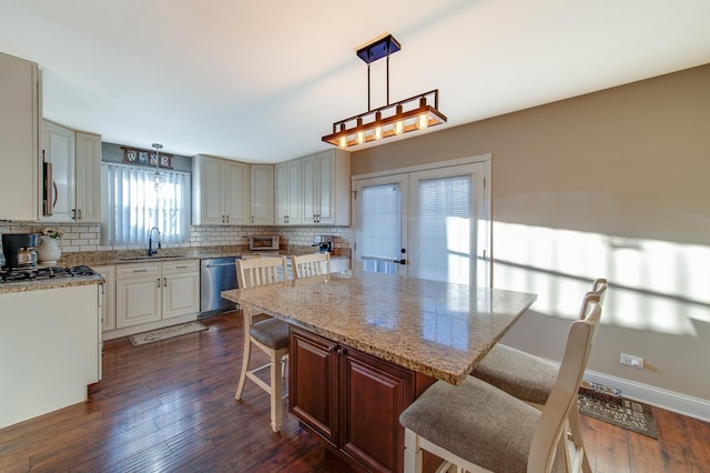 kitchen with pendant lighting, a kitchen island, a breakfast bar area, appliances with stainless steel finishes, and sink