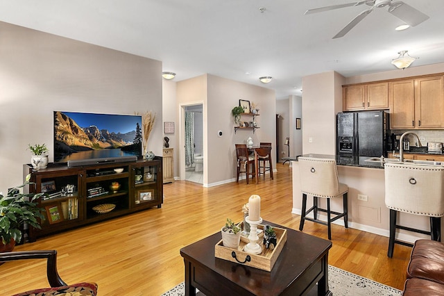 living room with ceiling fan, sink, and light hardwood / wood-style flooring