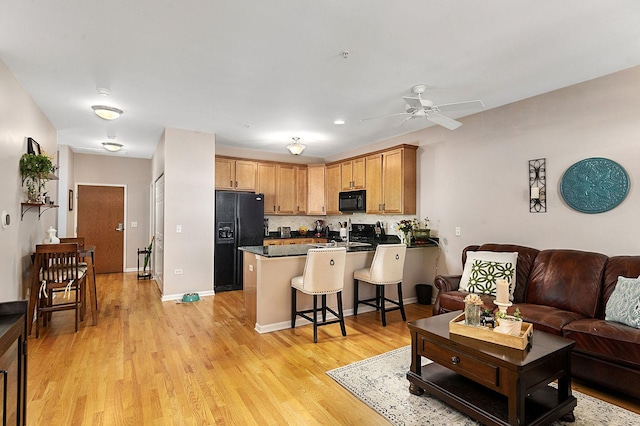 living room featuring ceiling fan and light hardwood / wood-style flooring