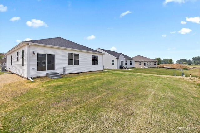 rear view of property with central air condition unit and a yard