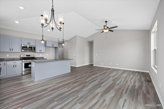 kitchen featuring stainless steel appliances, decorative light fixtures, a center island, lofted ceiling, and ceiling fan with notable chandelier