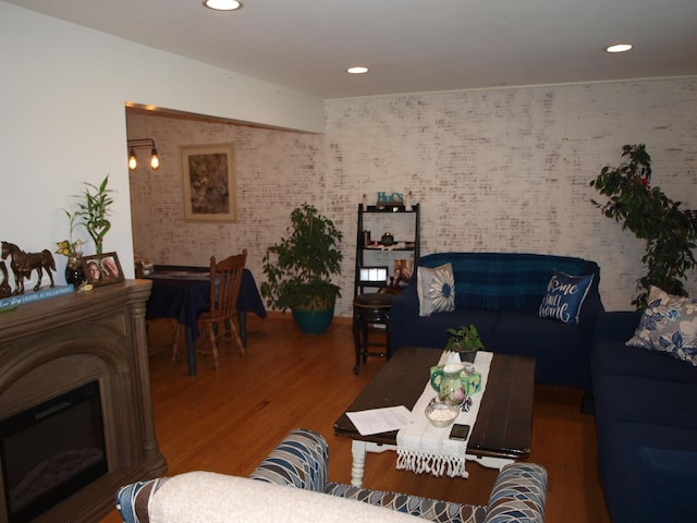 living room featuring brick wall, hardwood / wood-style flooring, and a fireplace