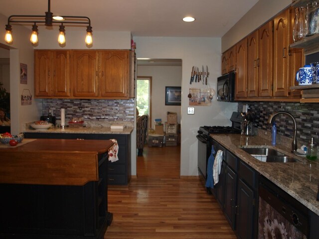 kitchen featuring sink, tasteful backsplash, black appliances, and light stone countertops