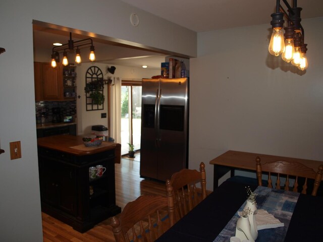 kitchen with stainless steel fridge, light hardwood / wood-style flooring, decorative backsplash, and hanging light fixtures