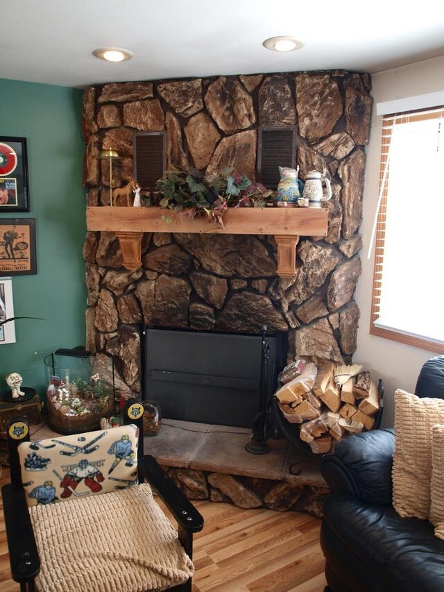 living room featuring wood-type flooring and a stone fireplace