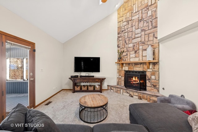 living room with carpet floors, vaulted ceiling, and a stone fireplace