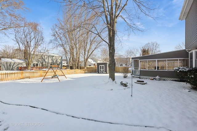 snowy yard featuring a playground and a storage unit