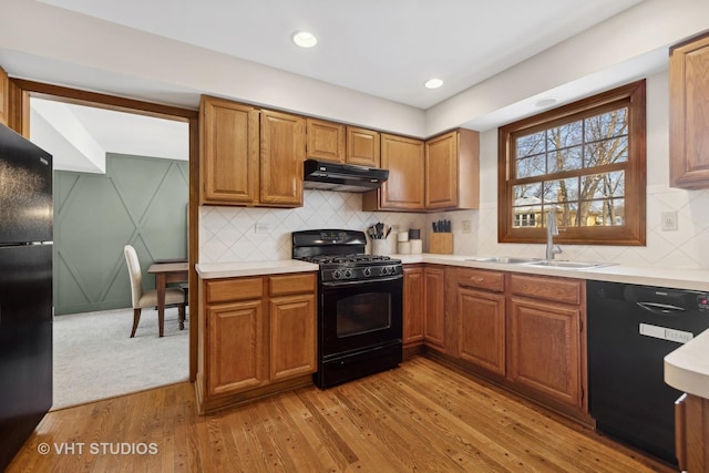 kitchen with black appliances, tasteful backsplash, light hardwood / wood-style flooring, and sink