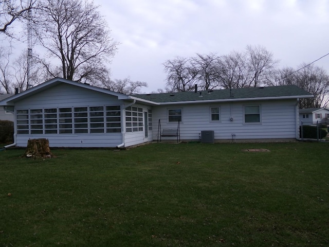 rear view of house with cooling unit, a yard, and a sunroom