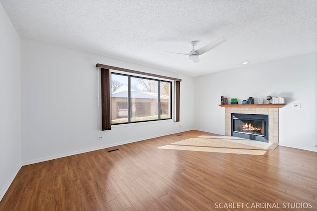 unfurnished living room featuring light hardwood / wood-style floors, a tile fireplace, and a textured ceiling