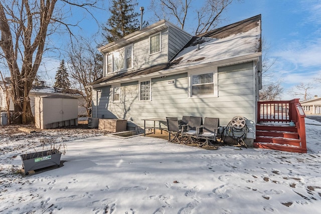 snow covered property with cooling unit and a shed