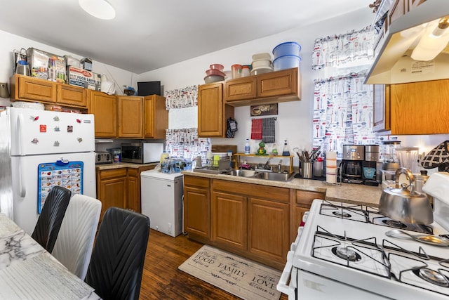 kitchen with sink, white appliances, dark wood-type flooring, and washer / dryer