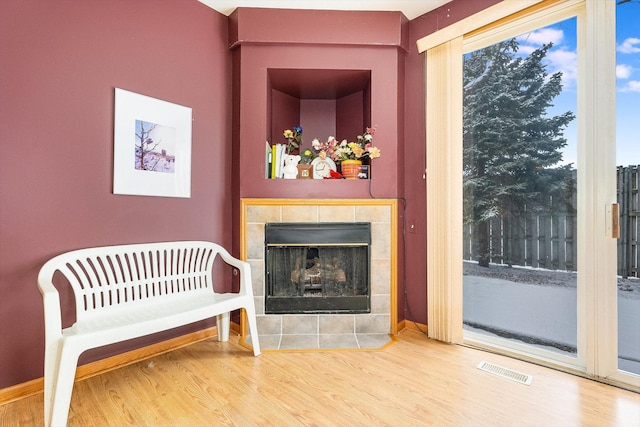 sitting room with hardwood / wood-style floors and a tile fireplace