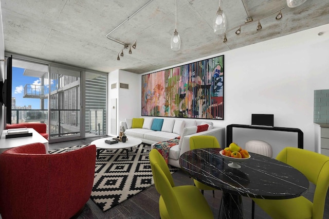 living area featuring rail lighting, floor to ceiling windows, visible vents, and wood finished floors