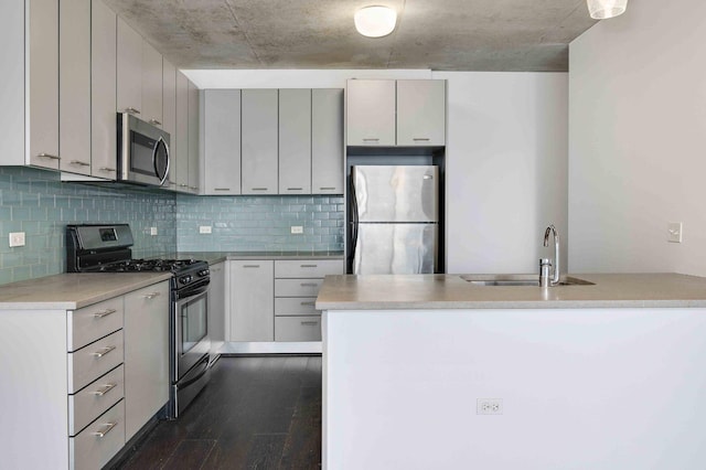 kitchen featuring a sink, light countertops, appliances with stainless steel finishes, backsplash, and dark wood finished floors