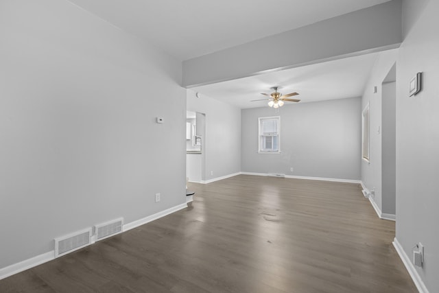 empty room featuring a ceiling fan, dark wood-style flooring, and baseboards