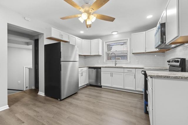 kitchen featuring stainless steel appliances, a sink, a ceiling fan, white cabinetry, and decorative backsplash