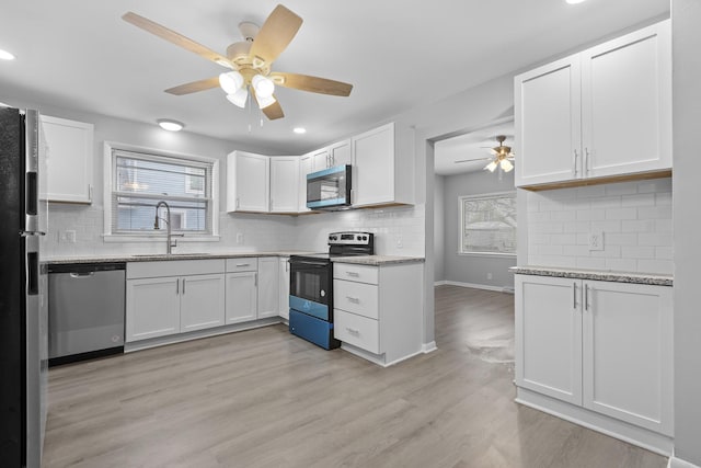 kitchen featuring stainless steel appliances, a sink, ceiling fan, white cabinets, and backsplash