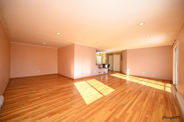 empty room featuring baseboard heating and light wood-type flooring