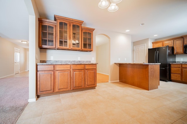 kitchen with black appliances, light colored carpet, and light stone countertops