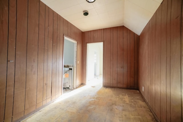 unfurnished room with vaulted ceiling and wooden walls