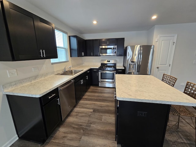 kitchen featuring dark wood-type flooring, a center island, stainless steel appliances, a breakfast bar area, and sink