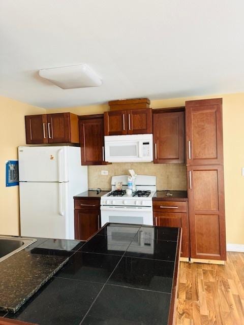 kitchen with white appliances, backsplash, and light hardwood / wood-style flooring