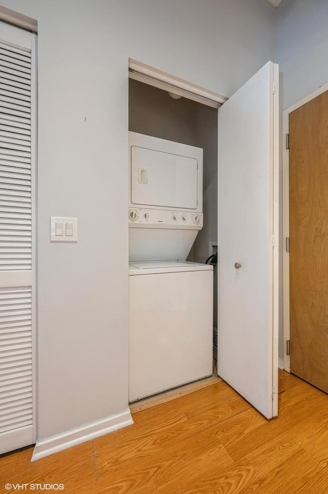 clothes washing area with light hardwood / wood-style floors and stacked washer and clothes dryer