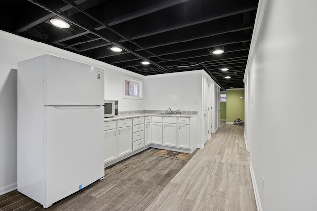 kitchen with hardwood / wood-style flooring, a healthy amount of sunlight, light stone countertops, white cabinets, and white refrigerator