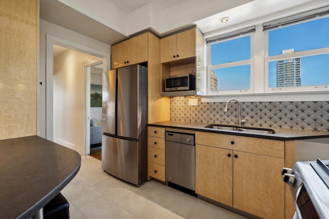 kitchen featuring sink, light tile patterned floors, backsplash, and appliances with stainless steel finishes