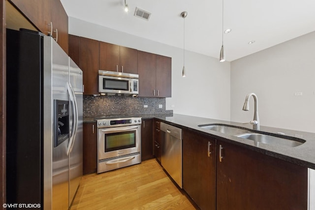 kitchen with light hardwood / wood-style flooring, sink, stainless steel appliances, kitchen peninsula, and tasteful backsplash