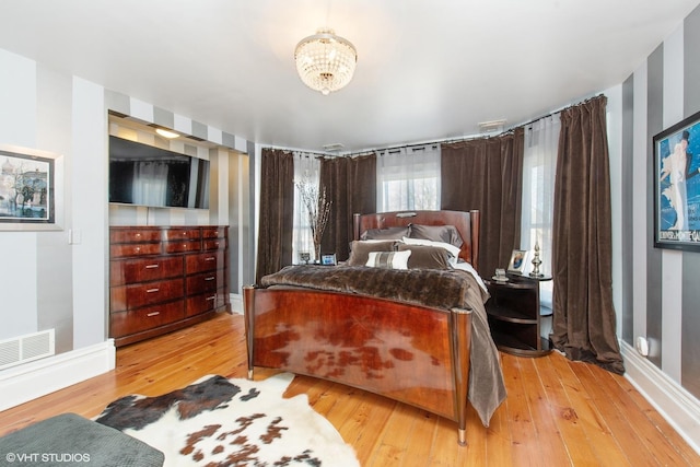 bedroom with a chandelier and light wood-type flooring