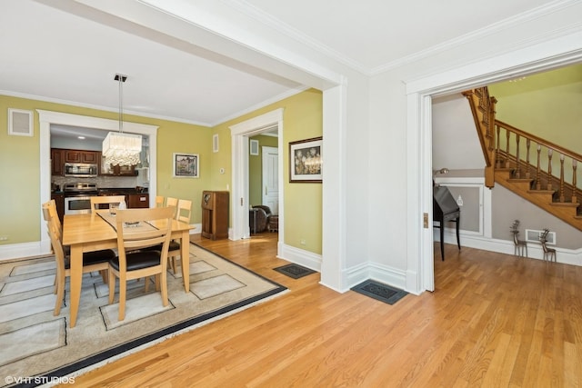 dining room featuring crown molding, light hardwood / wood-style floors, and a chandelier