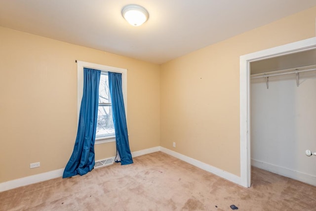 unfurnished bedroom featuring light carpet and a closet