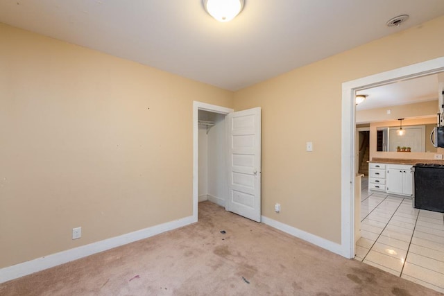 unfurnished bedroom featuring ensuite bathroom and light colored carpet