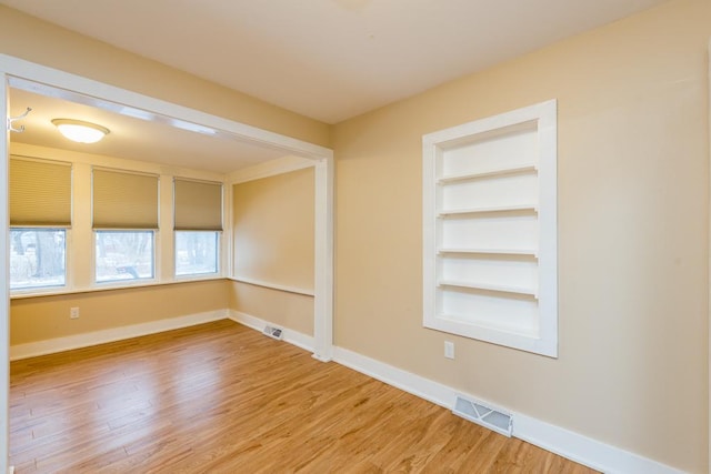 spare room with built in features and hardwood / wood-style flooring