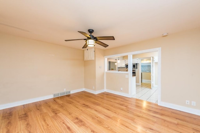 empty room with ceiling fan and light hardwood / wood-style flooring