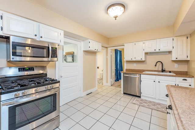 kitchen with white cabinets, appliances with stainless steel finishes, sink, and light tile patterned flooring