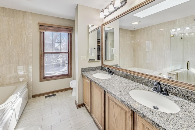 full bathroom featuring toilet, vanity, tile patterned flooring, a skylight, and shower with separate bathtub