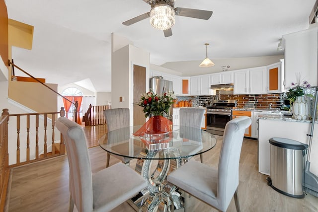 dining room featuring ceiling fan, light wood-type flooring, and vaulted ceiling