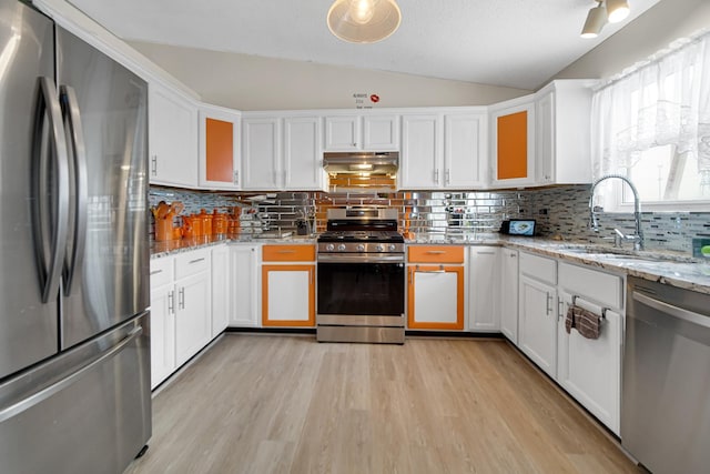 kitchen featuring stainless steel appliances, white cabinetry, sink, and vaulted ceiling