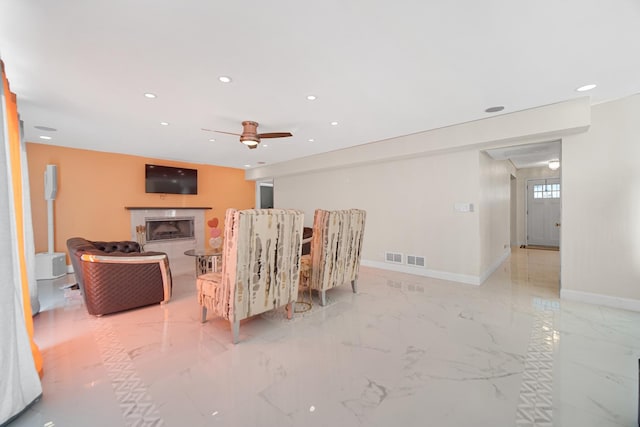 living room with a tile fireplace and ceiling fan