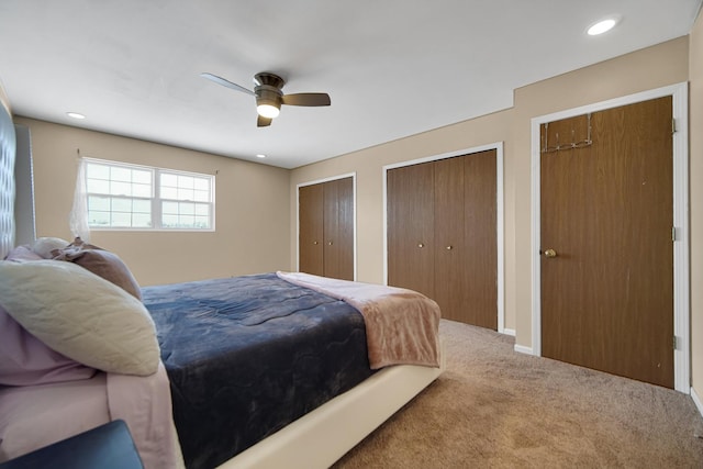 bedroom featuring ceiling fan, multiple closets, and carpet flooring