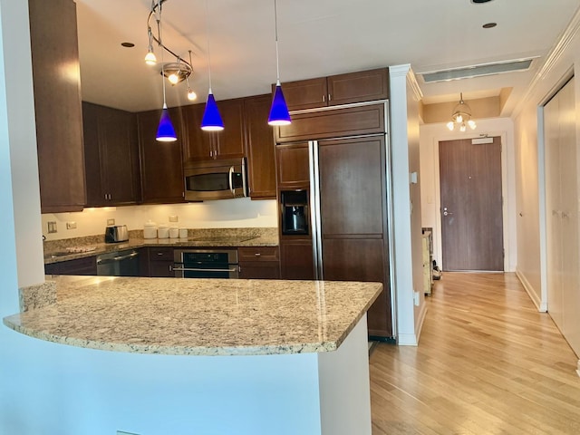 kitchen with decorative light fixtures, stainless steel appliances, kitchen peninsula, and light stone counters