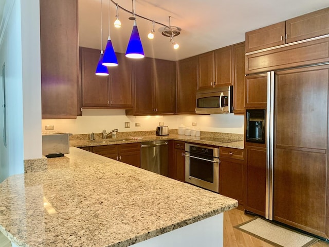 kitchen featuring appliances with stainless steel finishes, hanging light fixtures, and kitchen peninsula