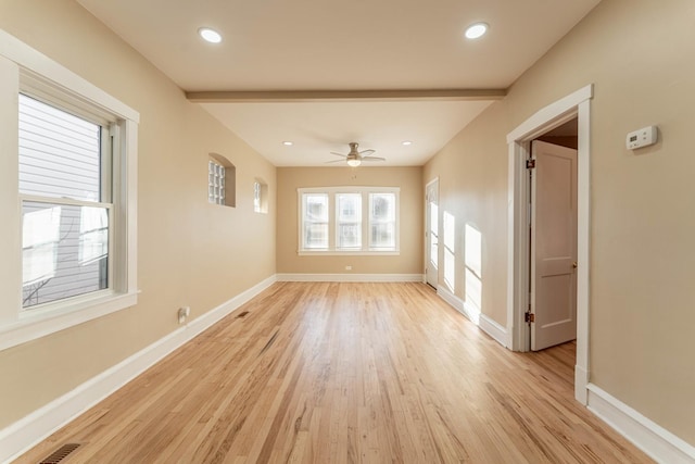 unfurnished room featuring ceiling fan, light wood-type flooring, and beamed ceiling