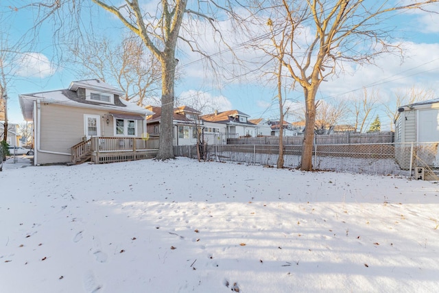 snow covered back of property with a deck