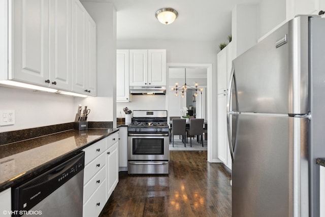 kitchen featuring white cabinetry, hanging light fixtures, dark hardwood / wood-style floors, dark stone counters, and appliances with stainless steel finishes