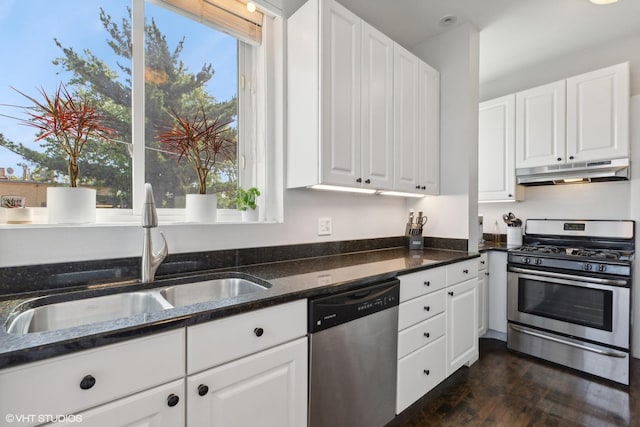 kitchen featuring dark wood-type flooring, white cabinetry, dark stone counters, appliances with stainless steel finishes, and sink