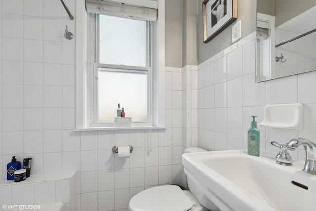 bathroom with tile walls, a shower, sink, and toilet